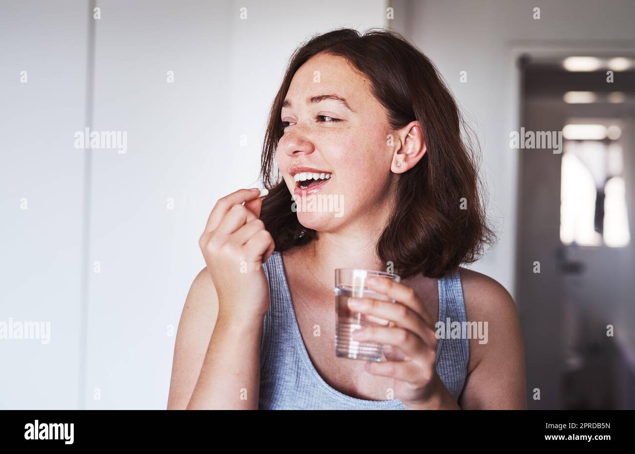 Fare ciò che serve per mantenere una buona salute. Una giovane donna che prende farmaci a casa. Foto Stock