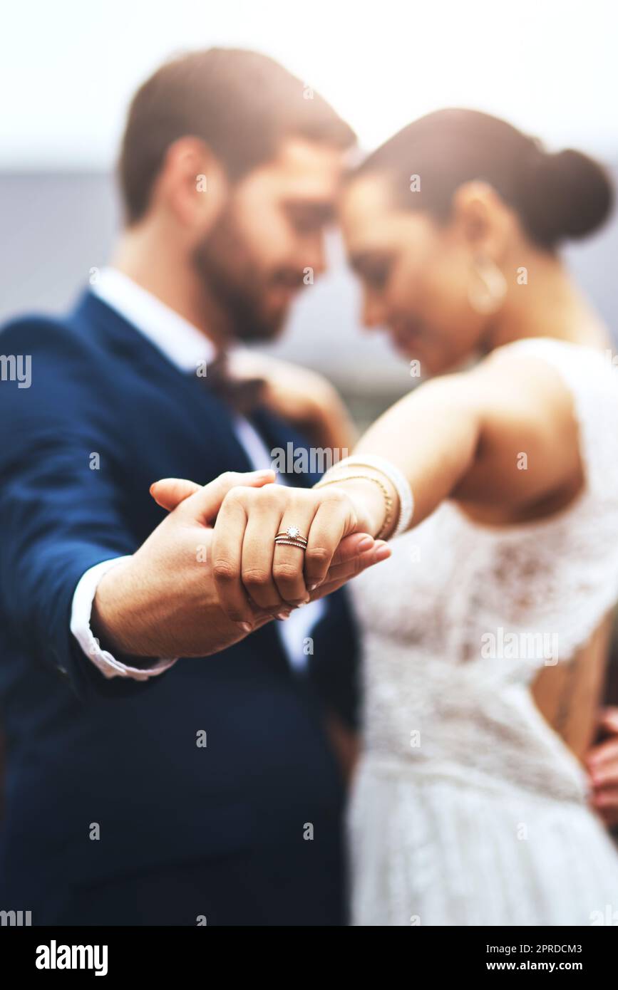 Im danzare in eterno con voi. Una giovane coppia allegra che tiene le mani e balla insieme il giorno del matrimonio. Foto Stock