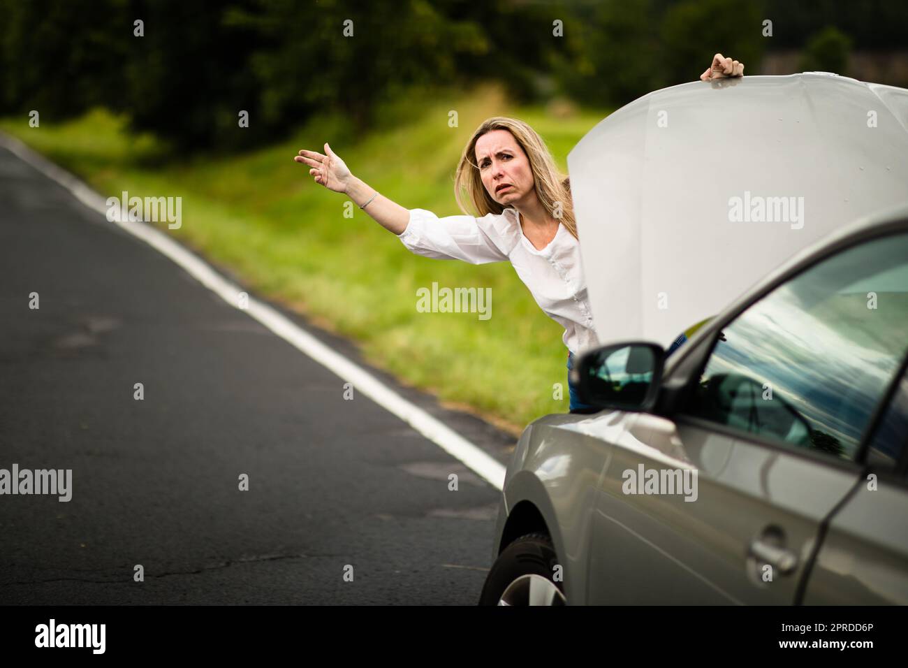 Bella donna di mezza età che ha problemi di automobile - ha rotto la macchina sul lato della strada, chiamando la compagnia di assicurazione per assistenza Foto Stock