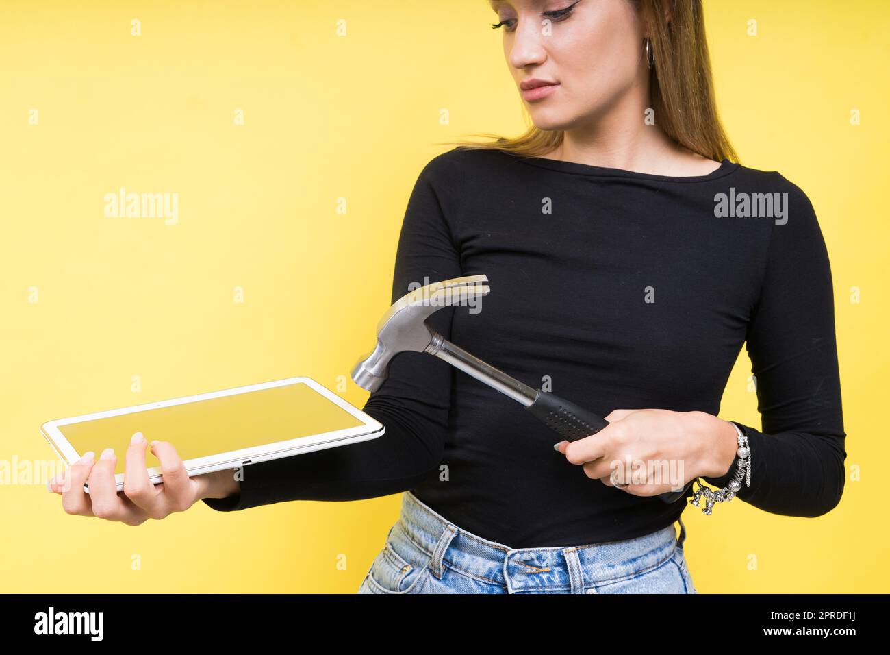 Centro servizi. Riparazione del notebook. Il cacciavite femmina svita i bulloni del computer portatile su sfondo giallo Foto Stock