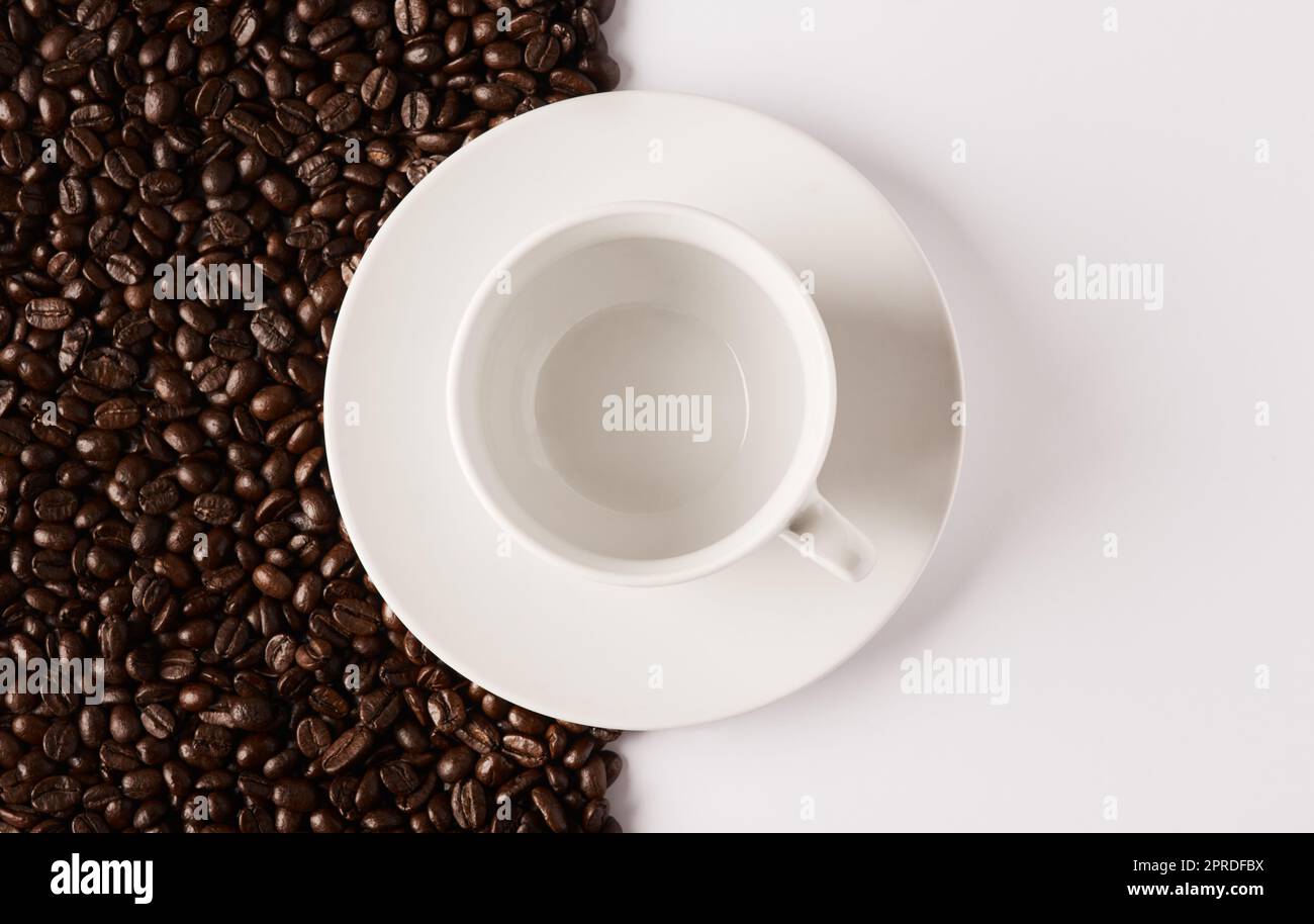 A caffè, o non a caffè... Primo piano di una tazza vuota e di un piattino su un fondo mezzo-e-mezzo di chicchi di caffè. Foto Stock