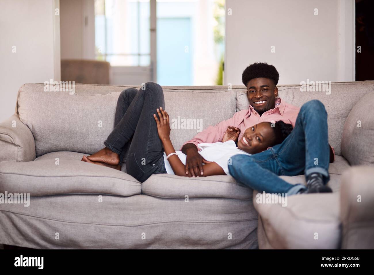 Ci è piaciissima una buona giornata di relax. Una giovane coppia felice si rilassa sul divano di casa. Foto Stock