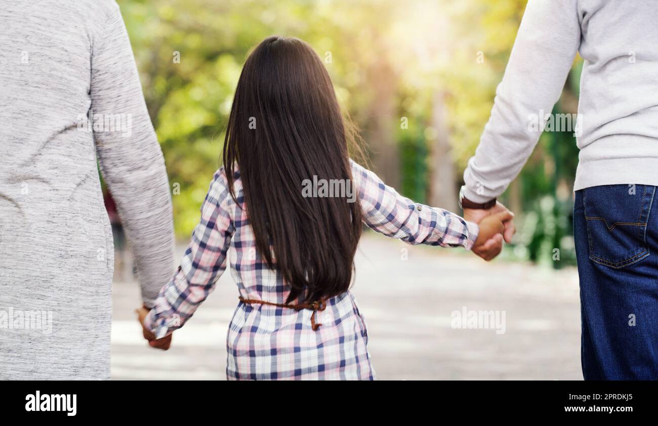 Tramandare il nostro amore da una generazione all'altra. Foto retrovisiva di una bambina irregistrabile che si tiene per mano con i nonni mentre cammina attraverso il parco. Foto Stock