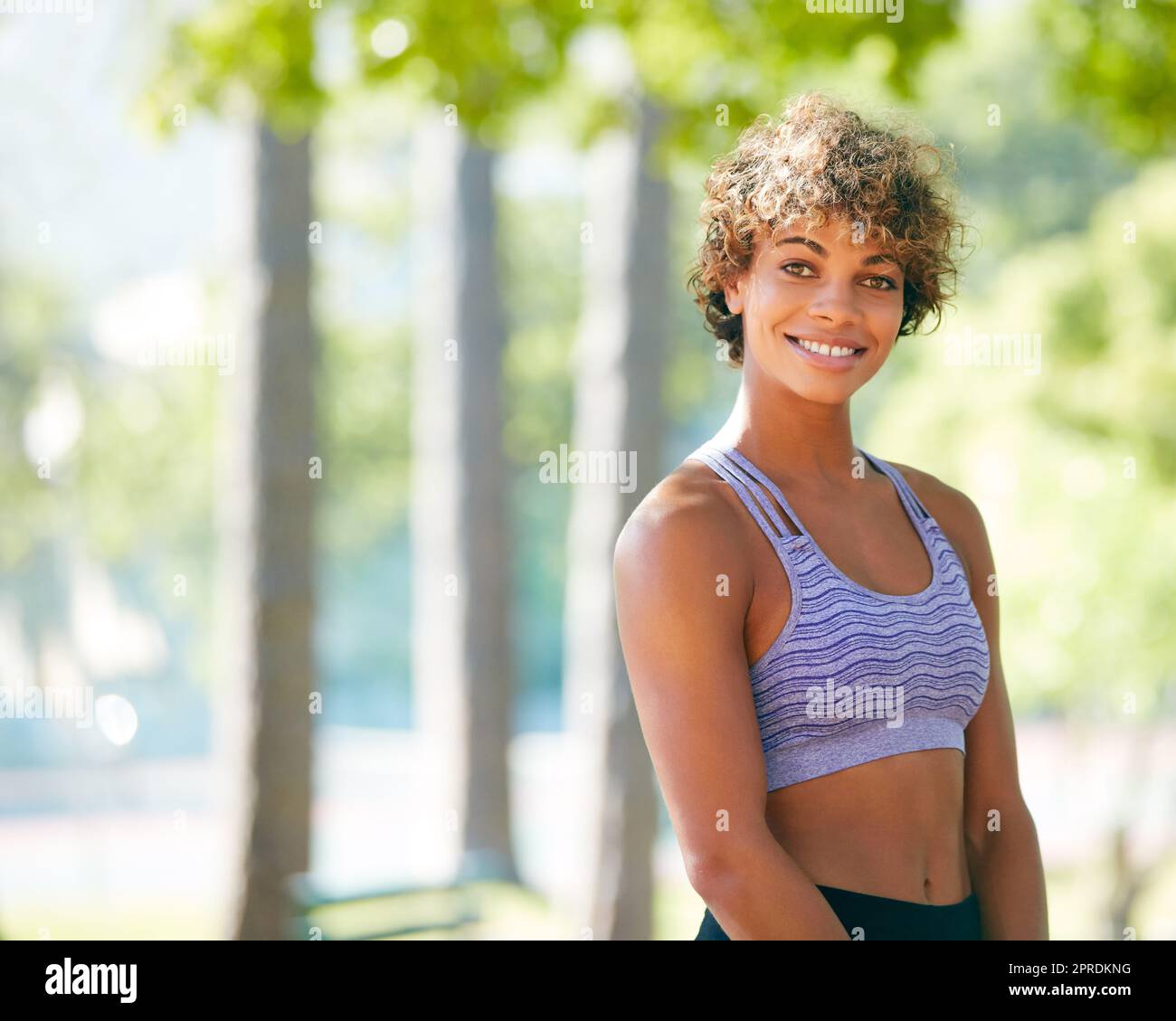 Felice di essere in forma. Una giovane donna sportiva in piedi all'aperto. Foto Stock