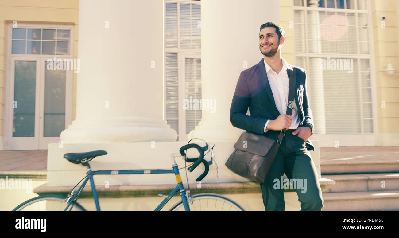 Questo clima ha fatto di tutto buon umore, un bel giovane uomo d'affari che si mette in posa accanto a una bicicletta in città. Foto Stock