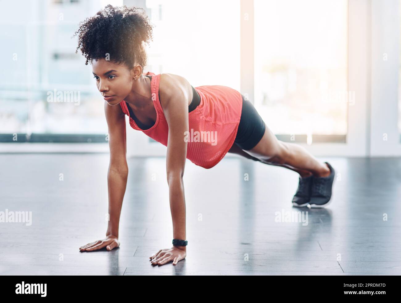 Ottenga dentro tanto esercitazione come possibilmente potete. Una giovane donna attraente che fa i push-up in uno studio. Foto Stock