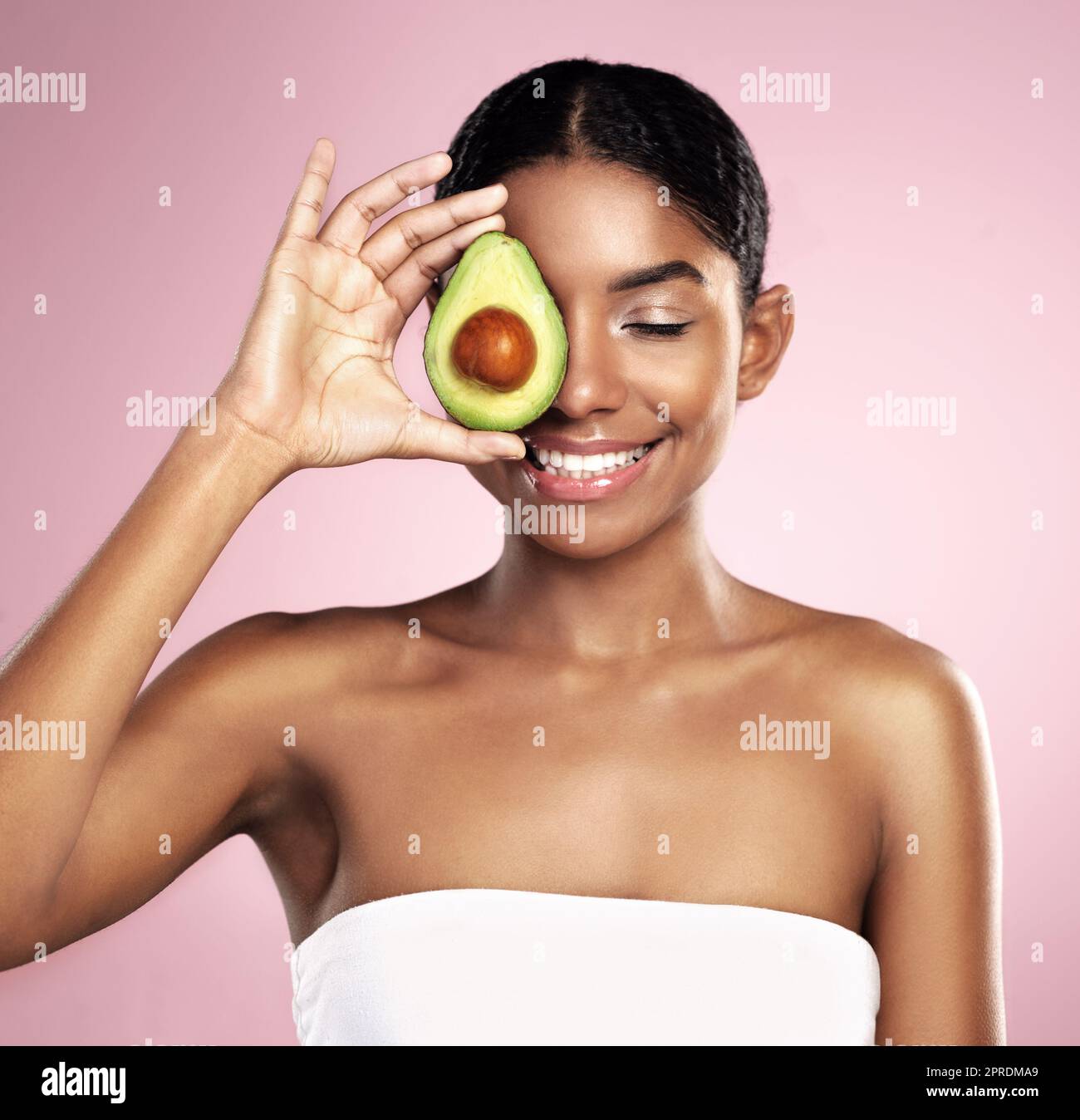 Credo in avocado per la cura della pelle. Studio di una bella giovane donna in posa con un avocado dimezzato. Foto Stock