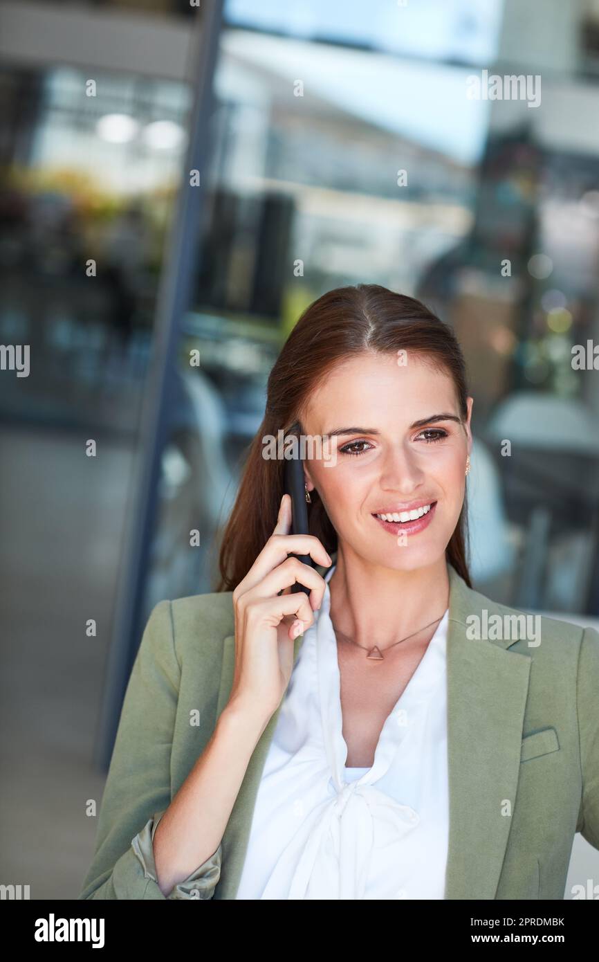 Meraviglioso, lascia organizzare quello. Una giovane donna d'affari che usa un telefono cellulare in un ufficio moderno. Foto Stock