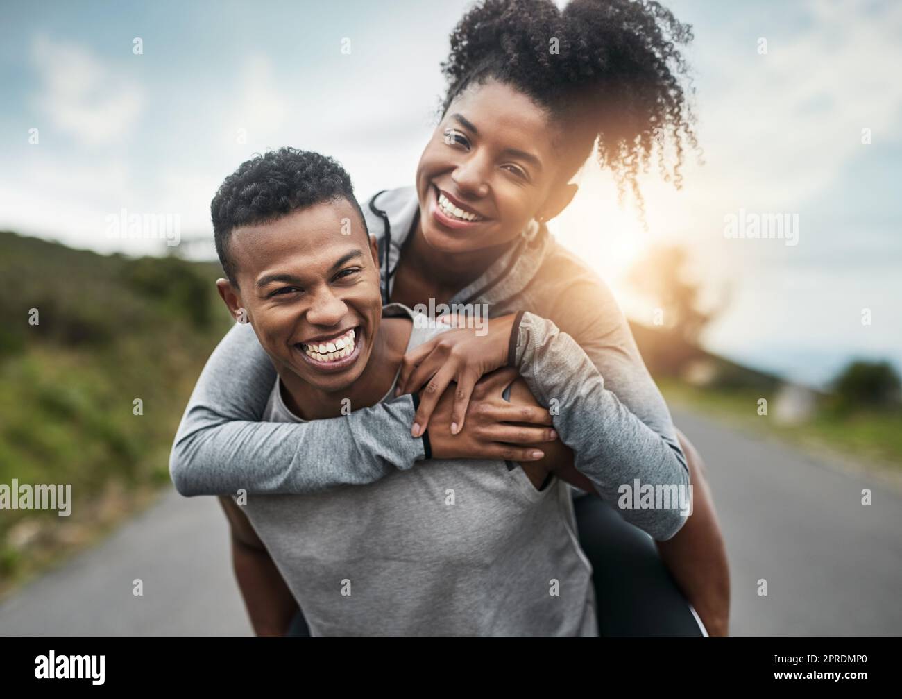 Ci portiamo l'un l'altro. Ritratto corto di un bel giovane sportivo piggybacking la sua giovane ragazza atletica fuori. Foto Stock