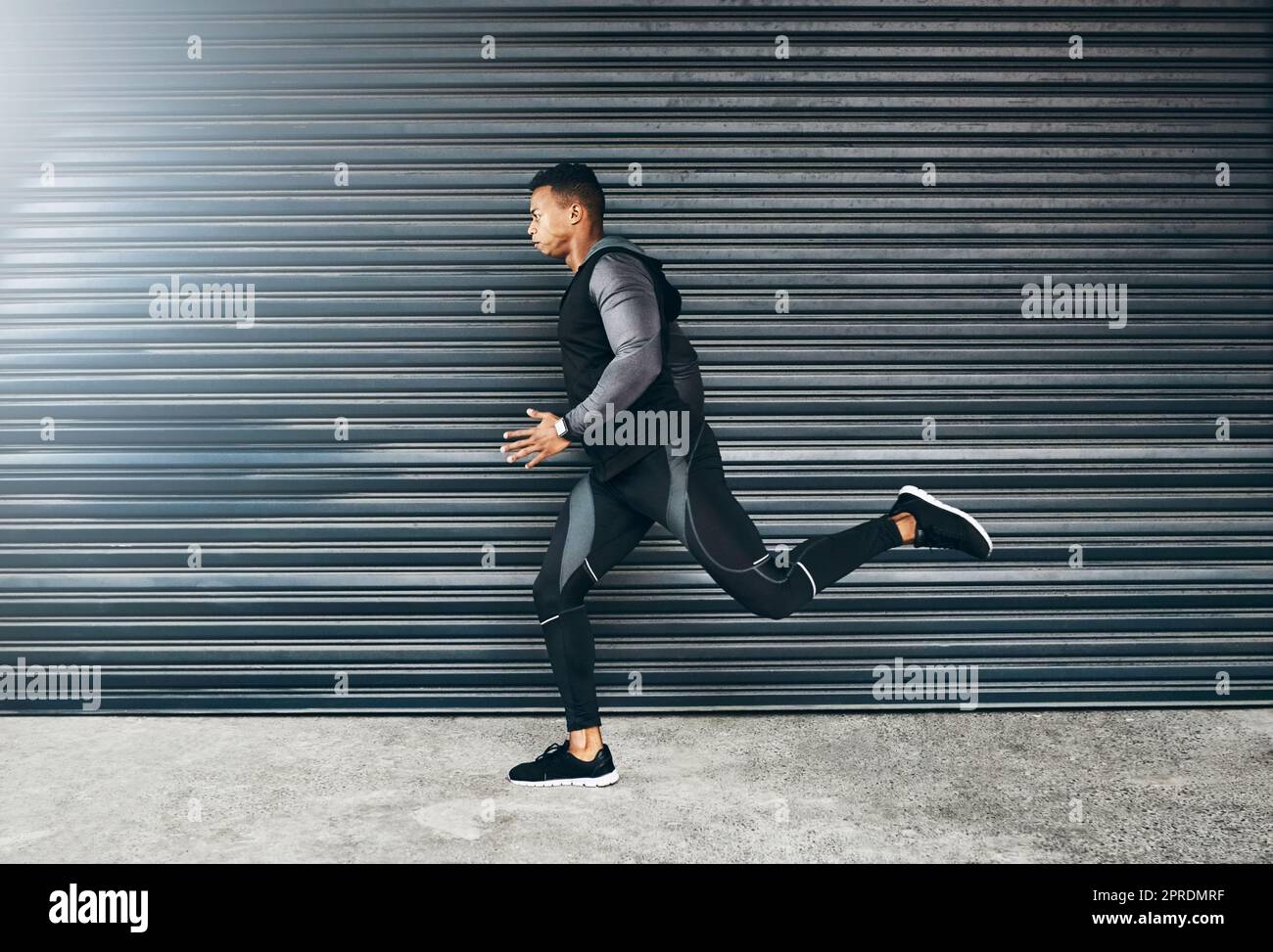 Tutto è possibile attraverso l'autodisciplina. Un giovane sportivo che corre su uno sfondo grigio. Foto Stock