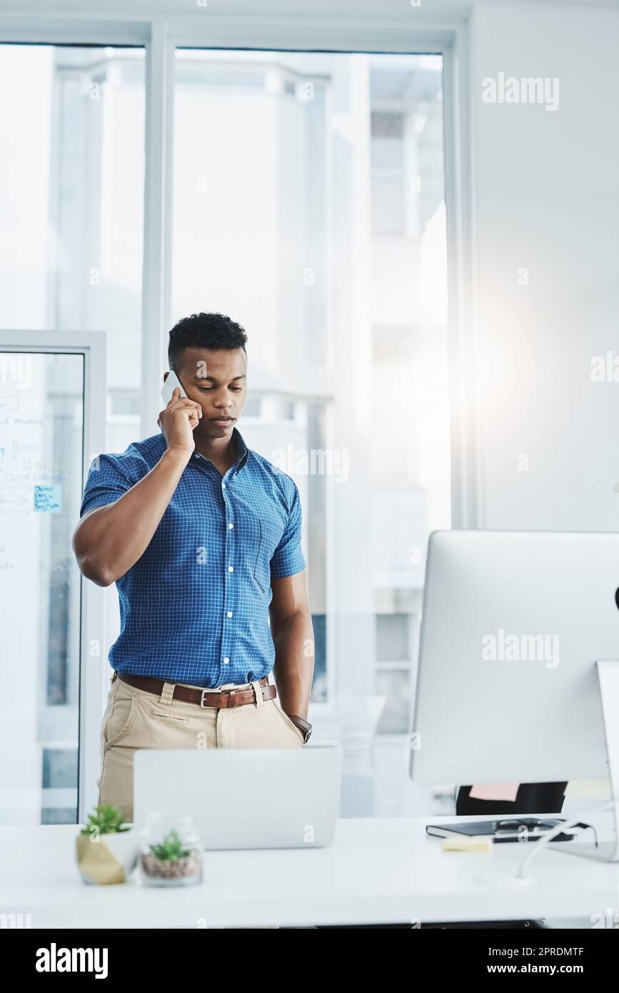 Un giovane uomo d'affari che parla su un cellulare in un ufficio. Foto Stock