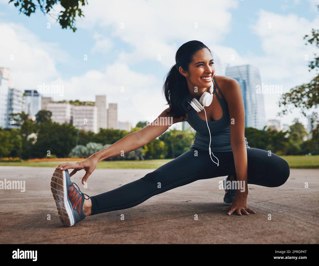 Sorridete il vostro modo di allenarvi. Scatto a tutta lunghezza di un giovane sportivo attraente facendo esercizi di stretch all'aperto in città. Foto Stock