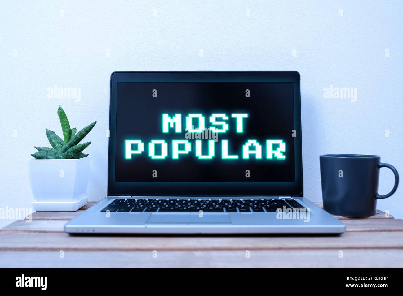 Cartello di testo che mostra i più popolari. Vetrina aziendale gradita seguita apprezzata dalla maggior parte della mostra in una società Lap Top con importanti informazioni sul tavolo con pianta e tazza di caffè. Foto Stock