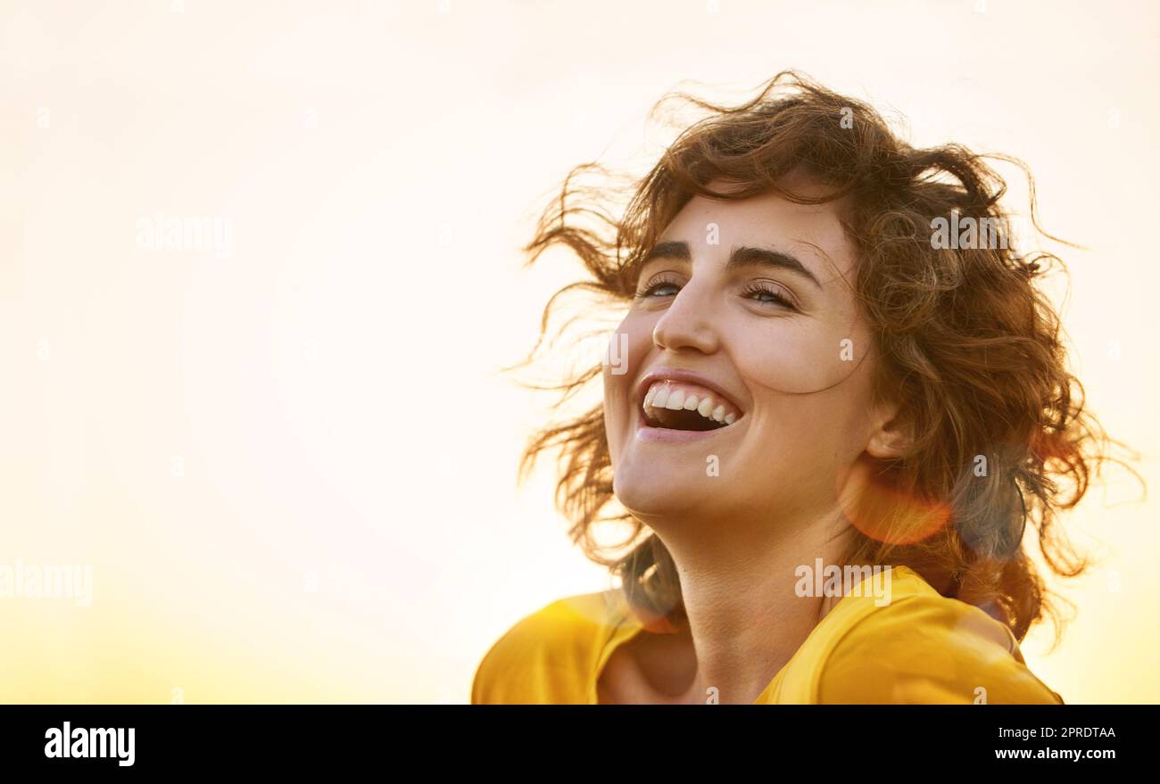 Giovane donna rida, retrò e alla moda con un'espressione vivace, sorridente e allegra sul suo viso all'aperto che sembra spensierata e fresca d'estate. Bella ragazza in uno stile elegante e luminoso per la primavera Foto Stock