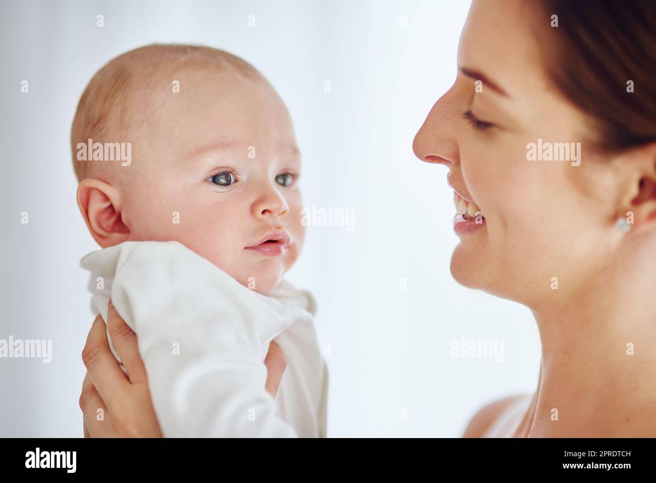 Una giovane madre felice che abbraccia il suo bambino carino a casa e si unisce mentre si gode la genitorialità. Genitore single giocoso e affettuoso, che abbraccia momenti preziosi con il suo bambino appena nato Foto Stock