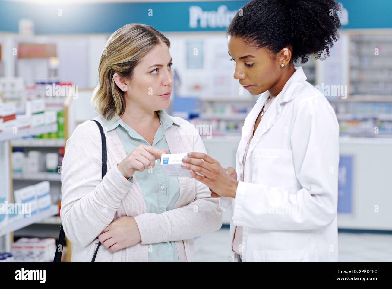 Sempre pronto a rispondere a tutte le vostre domande sulla salute. Un giovane farmacista che raccomanda un prodotto sanitario a una giovane donna in farmacia. Foto Stock