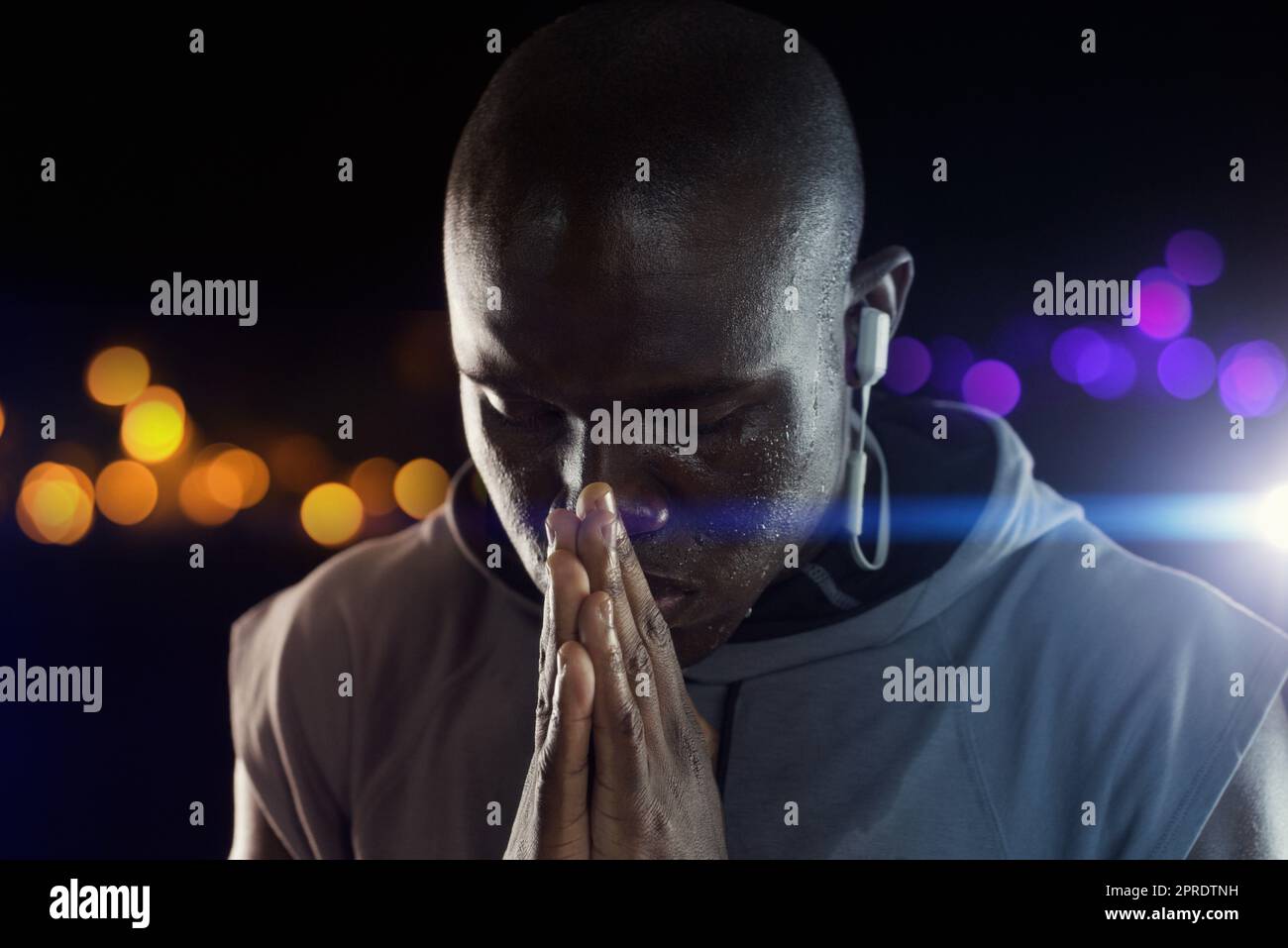 Le preghiere silenziose vanno molto lontano. Studio shot di un giovane sportivo che tiene le mani insieme in preghiera su uno sfondo scuro. Foto Stock