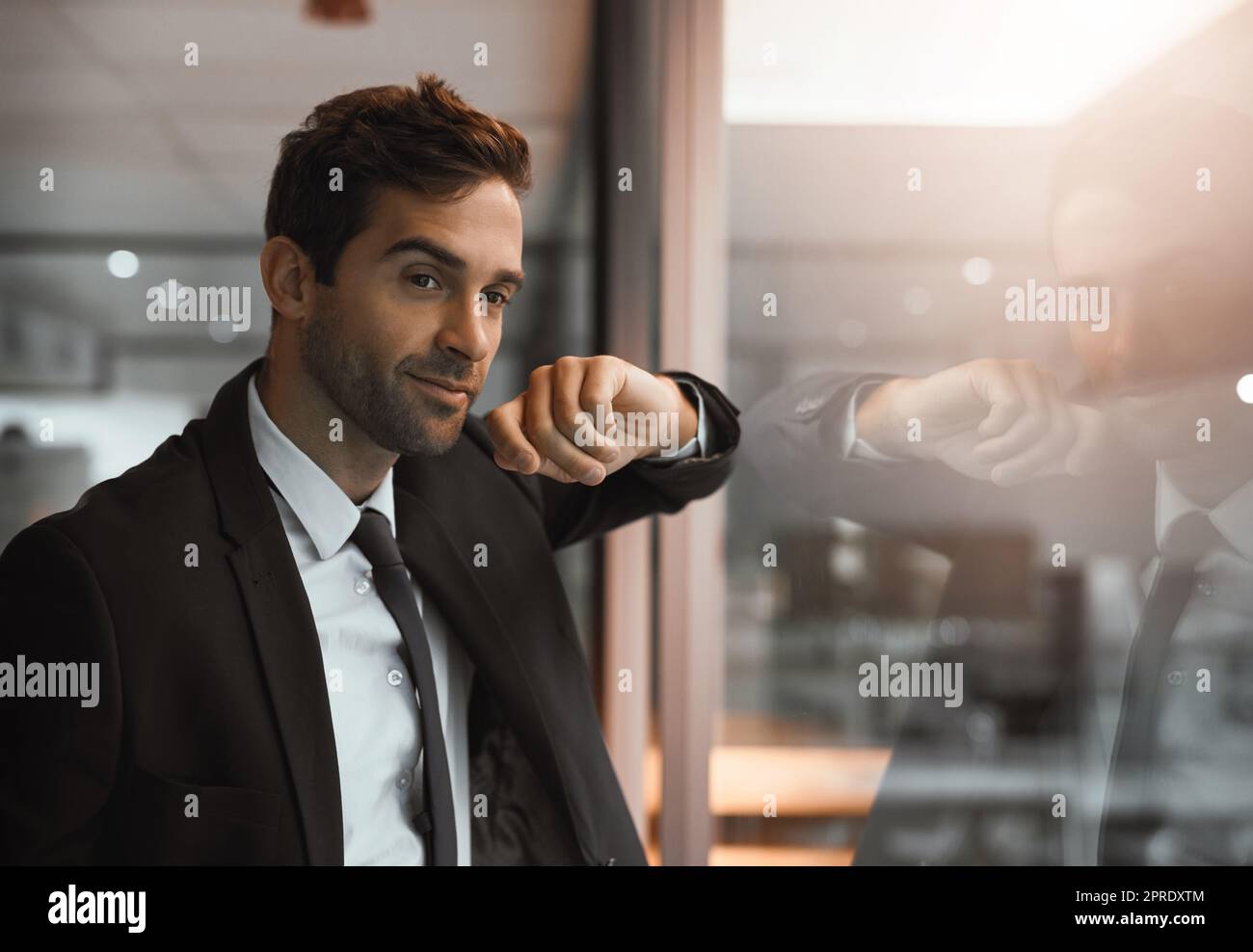 Il successo lo soddisfa bene. Un giovane uomo d'affari che guarda premuroso in un ufficio. Foto Stock