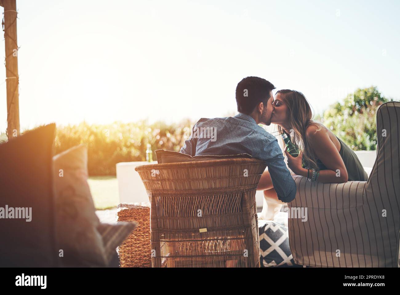 Solo per le labbra. Ripresa di una giovane coppia affettuosa baciandosi mentre si gustano alcune birre sul patio. Foto Stock