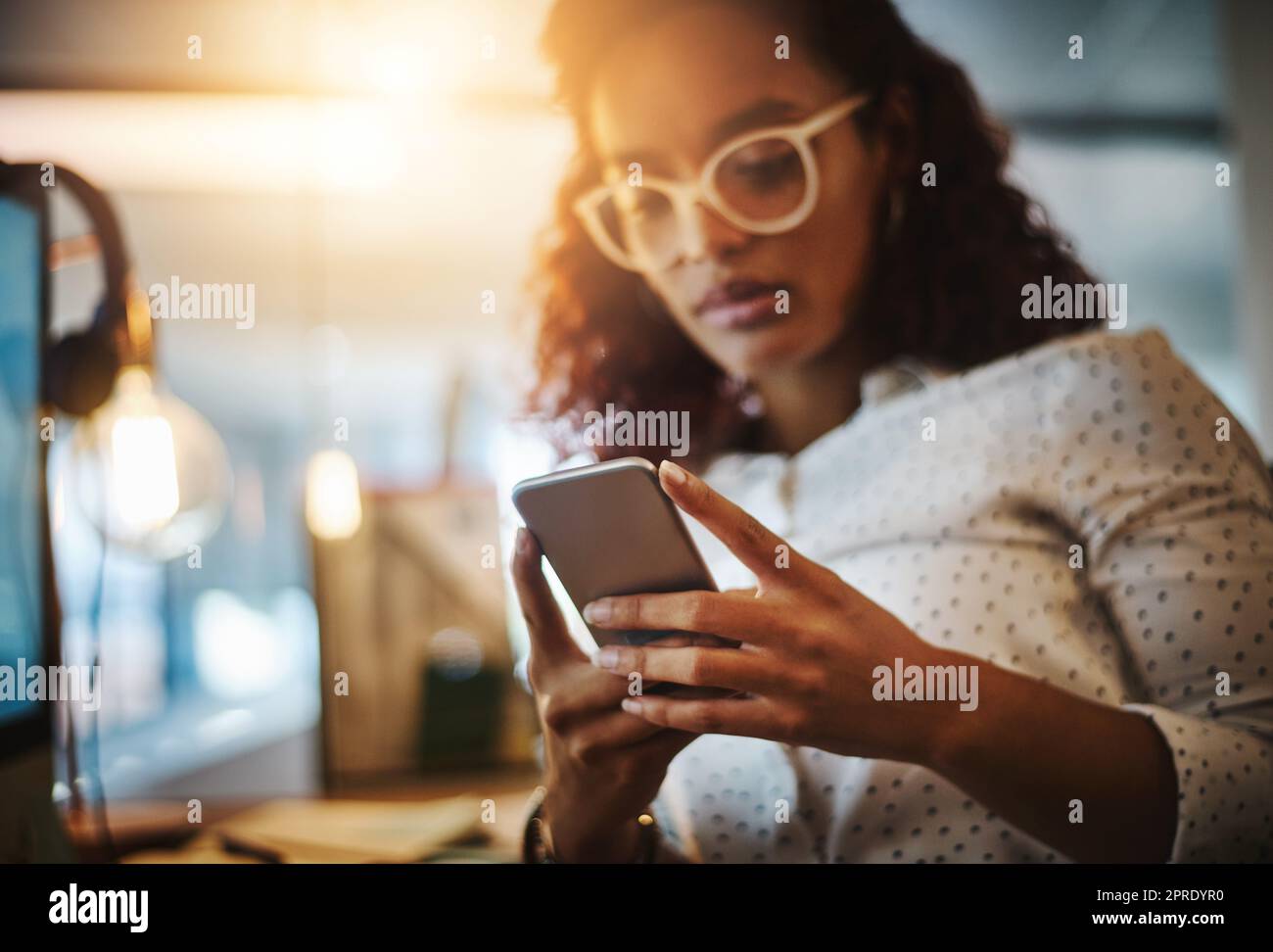 Non aspettate una giovane donna d'affari che usa un telefono cellulare durante la tarda notte al lavoro. Foto Stock