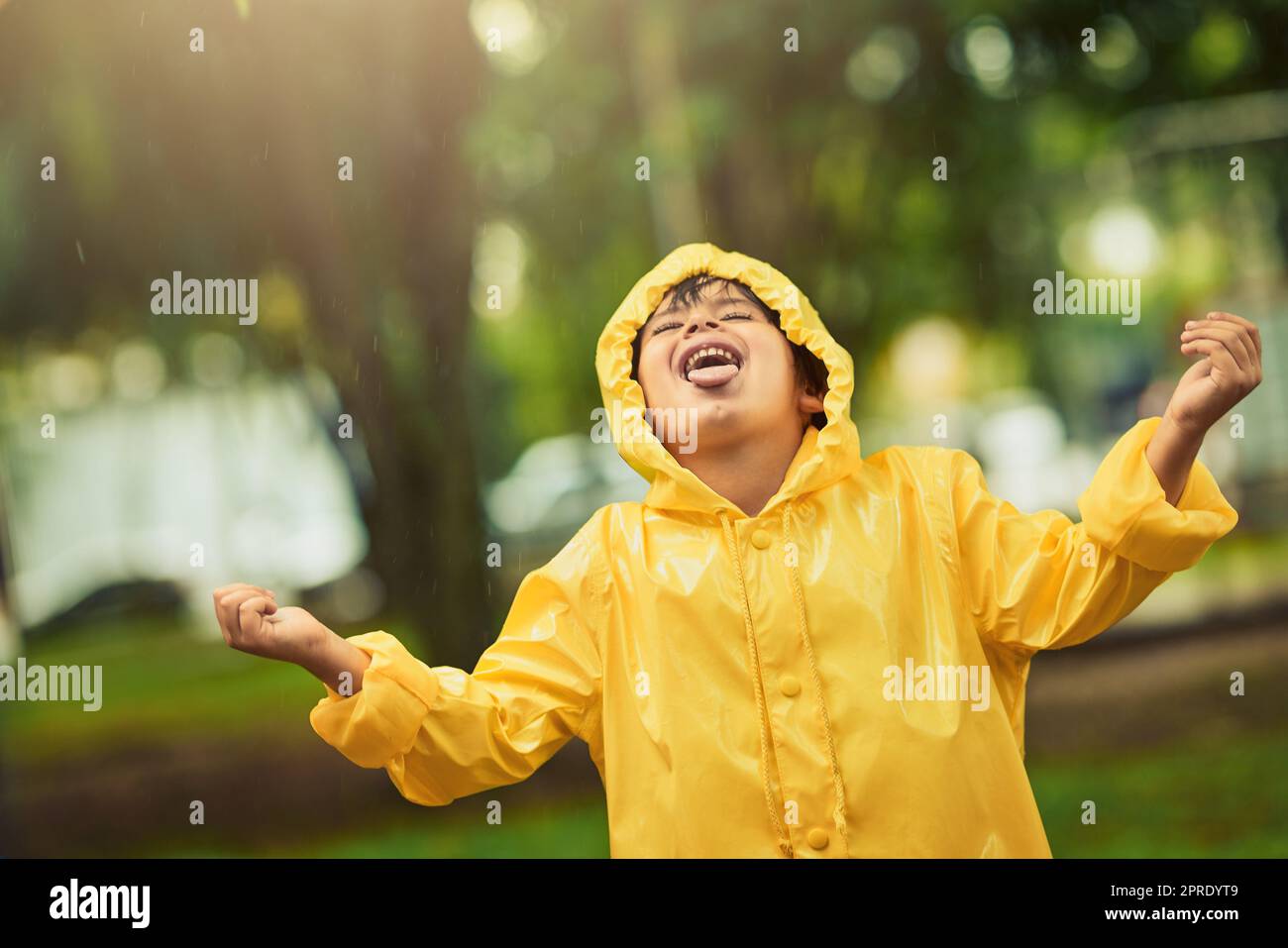 Alcuni si nascondono dalla pioggia, la abbraccia, un adorabile ragazzino sotto la pioggia. Foto Stock