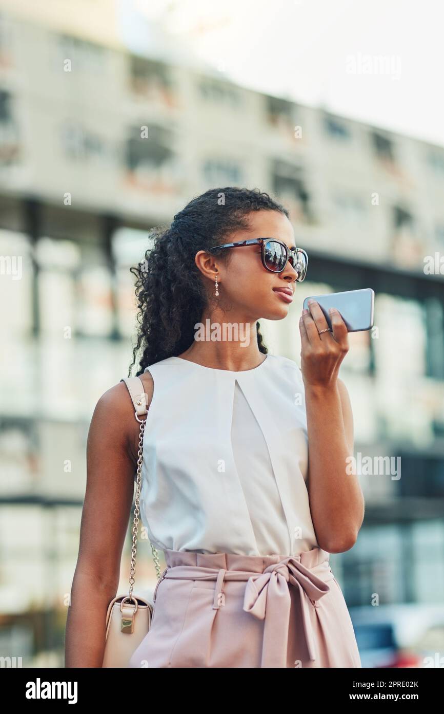 La vita urbana sta usando la tecnologia per muoversi. Una giovane donna attraente in una chiamata nella città. Foto Stock