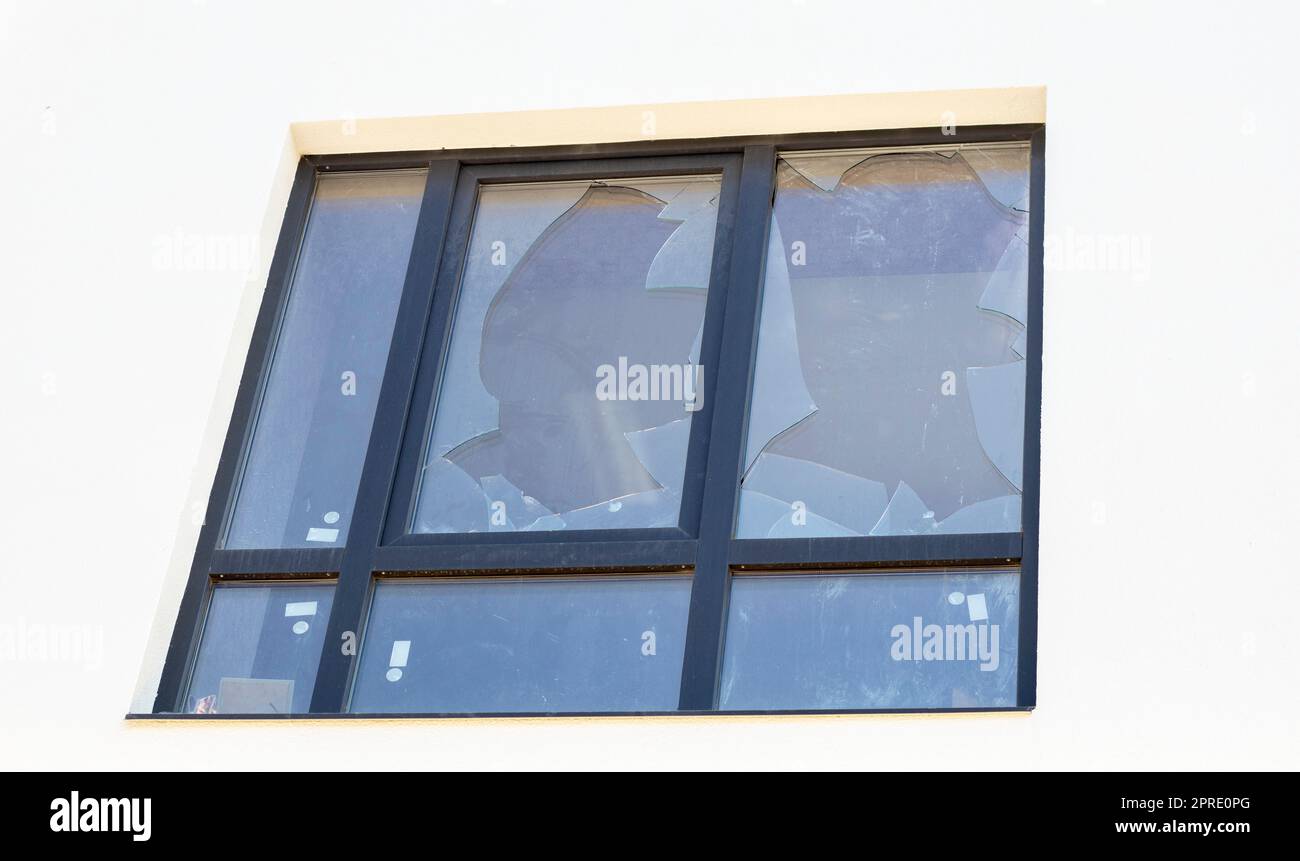 Finestra rotta di un edificio residenziale, frammenti di vetro affilati sporgono fuori. I combattimenti in Ucraina, la distruzione di edifici a causa di bombardamenti e attacchi missilistici da parte di un'ondata esplosiva. Foto Stock