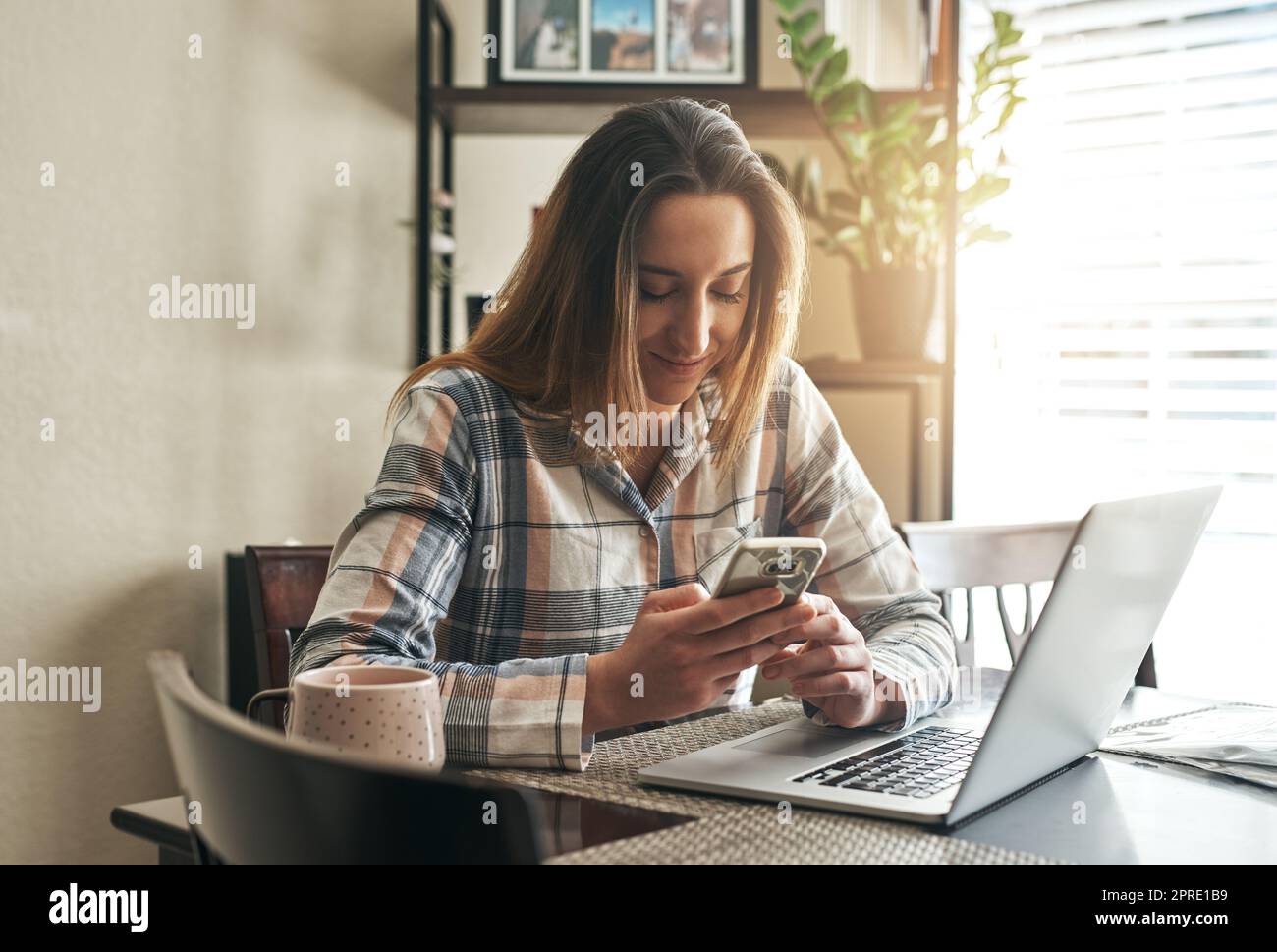 Le mattine sono quando controllo gli aggiornamenti. Una giovane donna che usa un portatile la mattina a casa. Foto Stock