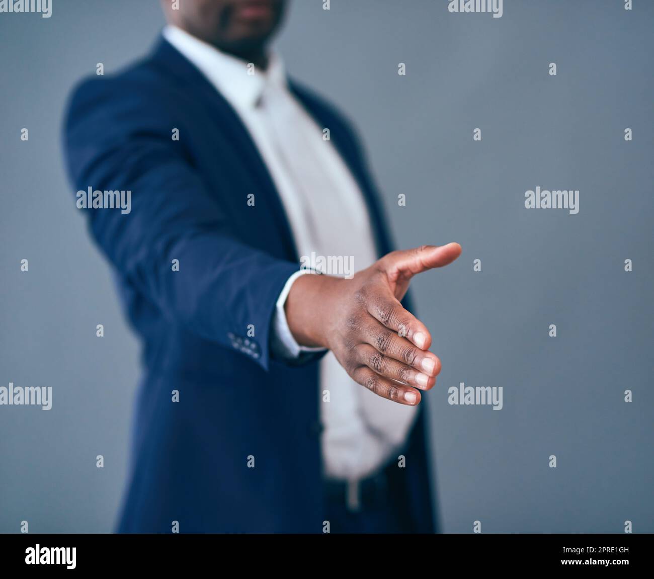 Alla creazione di nuove imprese. Foto in studio di un uomo d'affari irriconoscibile che mette la mano per una stretta di mano su uno sfondo grigio. Foto Stock