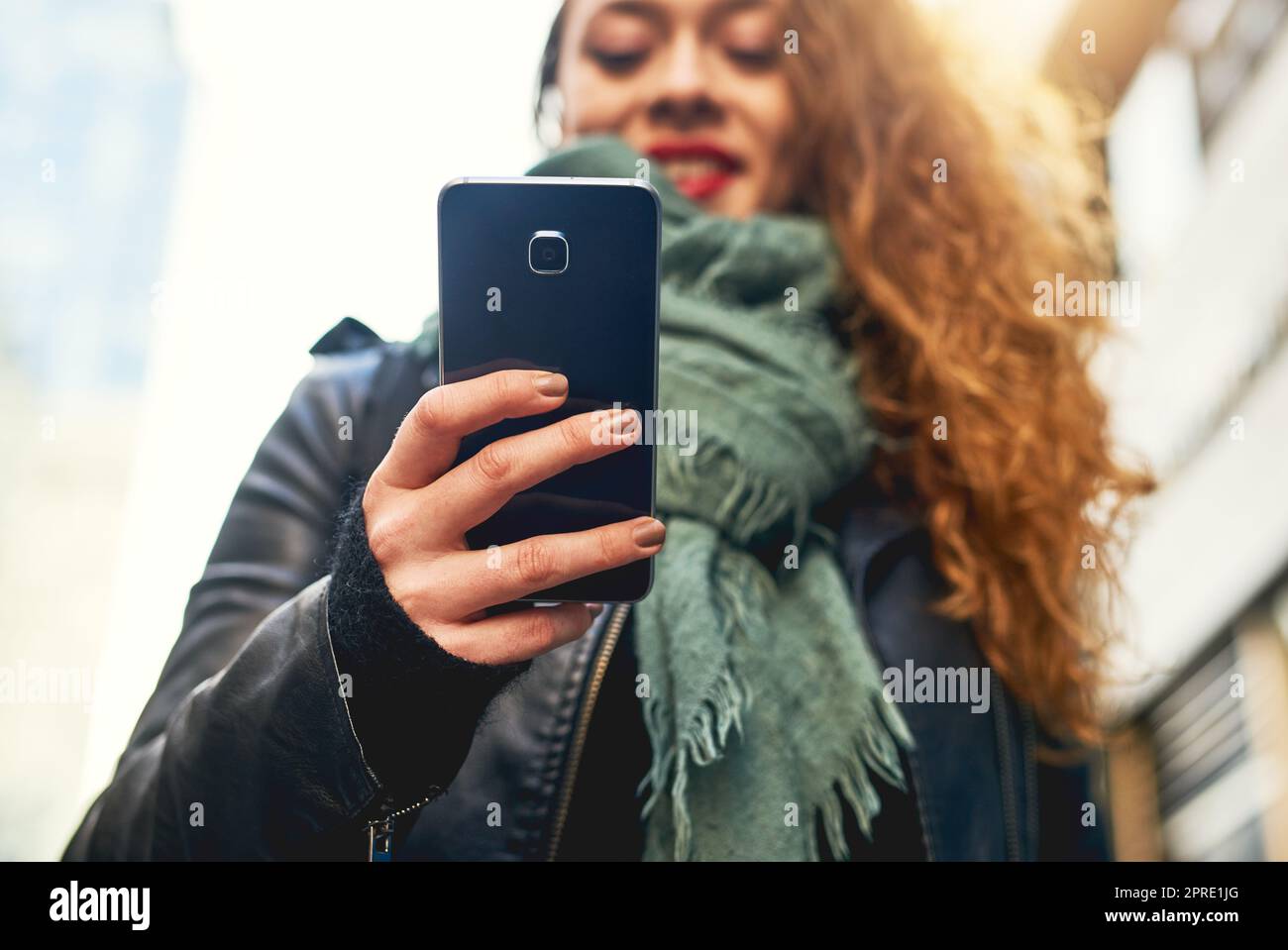 Cercare amici nelle vicinanze. Una giovane donna che usa il cellulare mentre si trova in città. Foto Stock