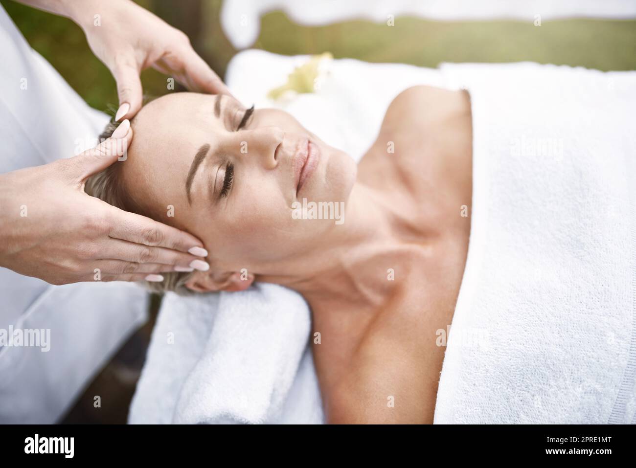 Libera la testa del lavoro e tutto il resto. Una donna di mezza età distesa sulla schiena mentre riceve un massaggio in una spa all'aperto durante il giorno. Foto Stock
