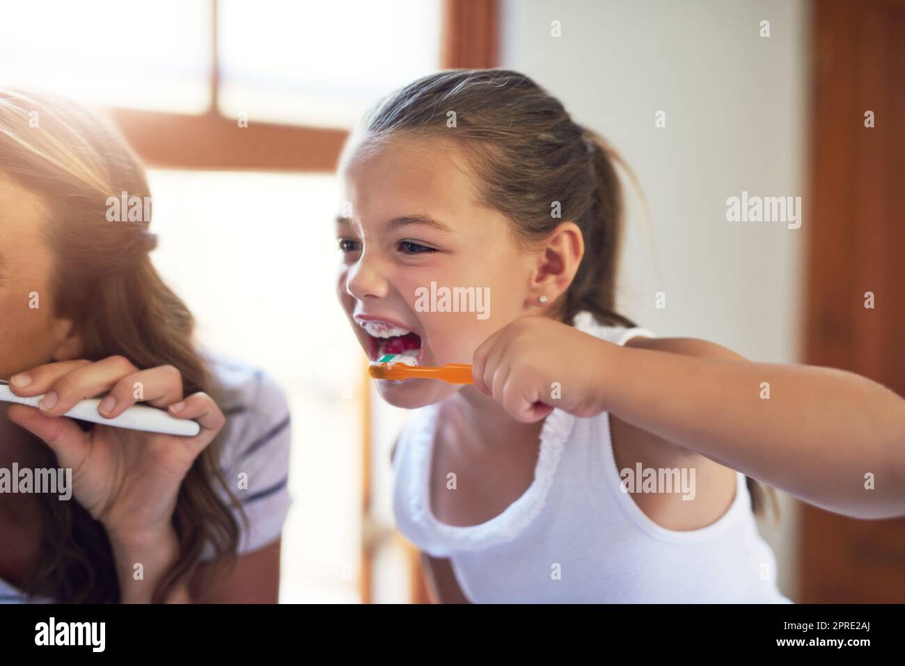 Le ceneri hanno ottenuto le perle piccole da prendere la cura di. Una ragazza piccola adorable che si boccola i suoi denti con la sua madre nel paese. Foto Stock