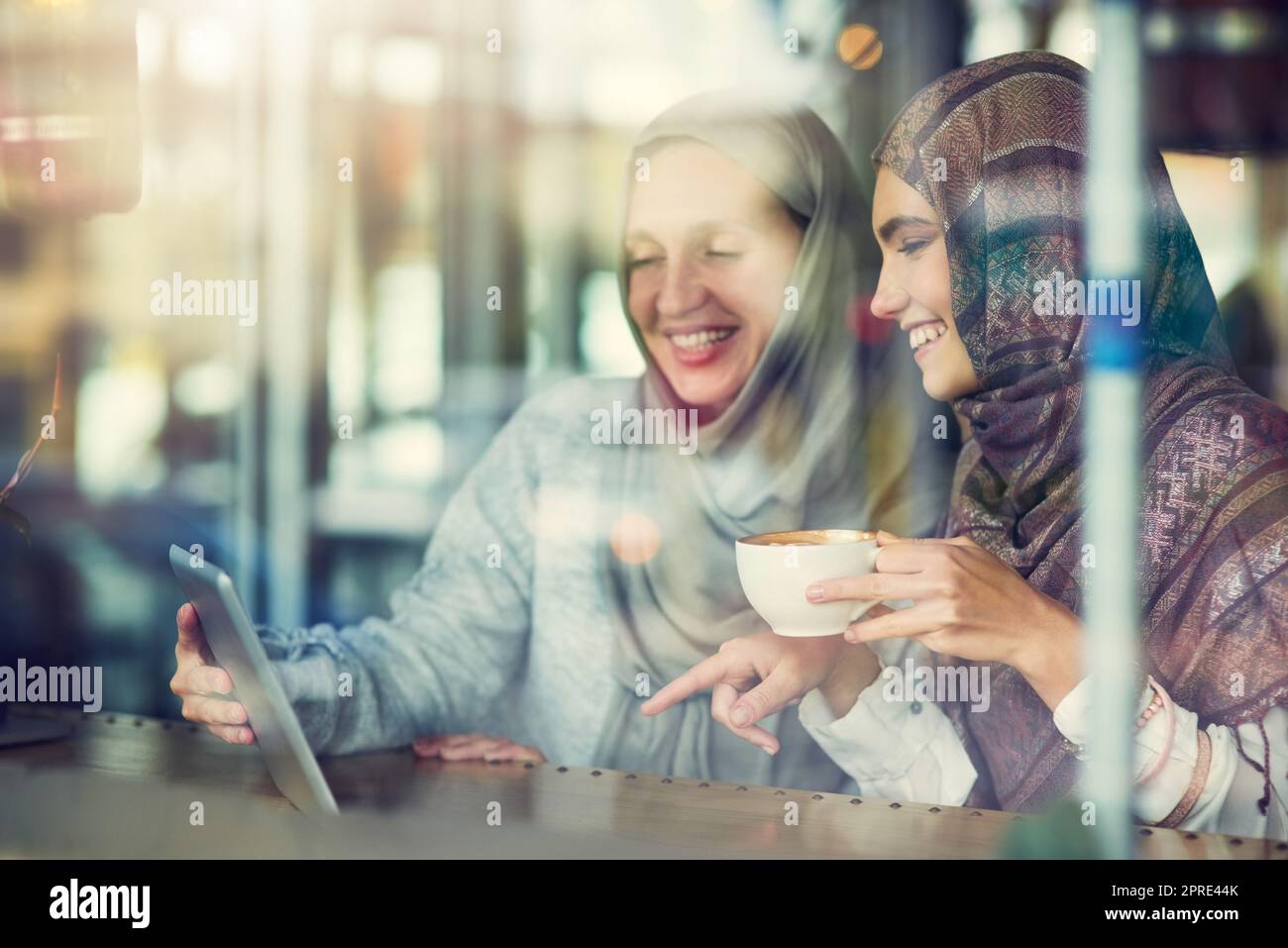 La tecnologia si connette online e nella vita reale. Due donne che utilizzano un tablet digitale insieme in un bar. Foto Stock