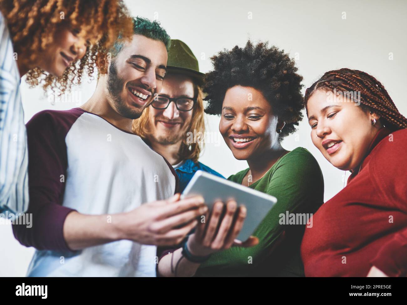 La generazione orientata ai media. Studio di un gruppo di giovani che utilizzano un tablet digitale insieme. Foto Stock