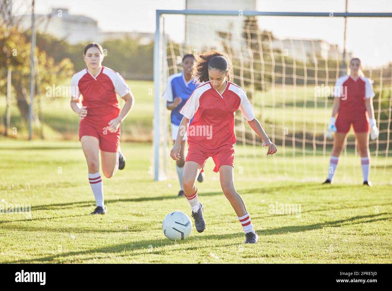 Calcio femminile, sport e squadre femminili che giocano partite sul campo mentre calci, placcano e corrono con una palla. Giocatori di calcio energici, veloci e abili in una partita competitiva contro avversari all'aperto Foto Stock