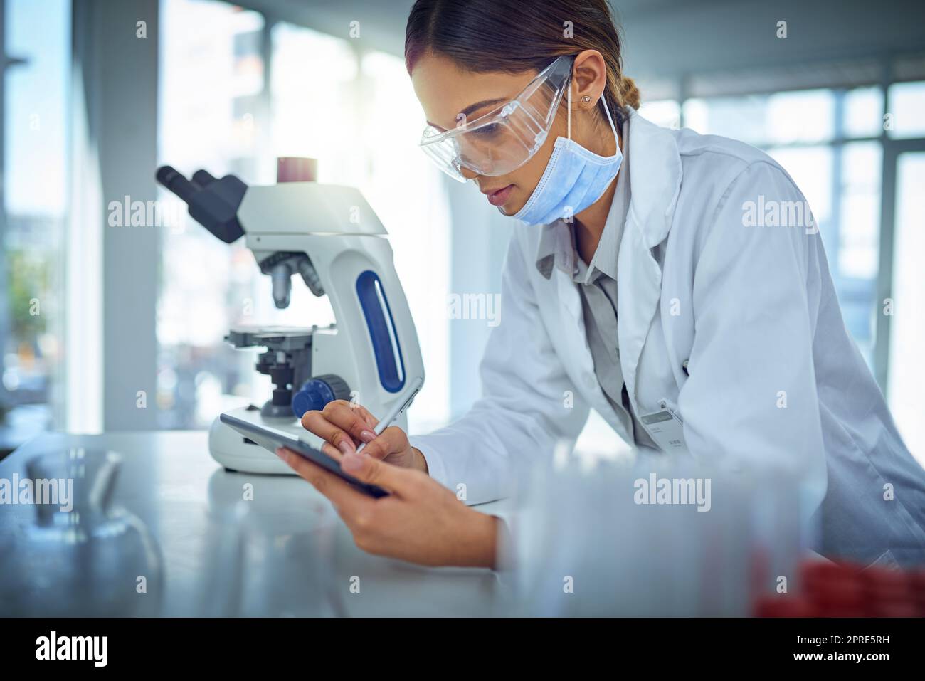 Raccolta di dati sul suo dispositivo. Una scienziata femminile che utilizza un tablet digitale in un laboratorio. Foto Stock