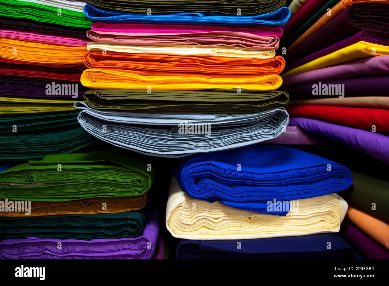 Varietà artistica tonalità colori tessuti impilati su scaffale del negozio in vendita Foto Stock