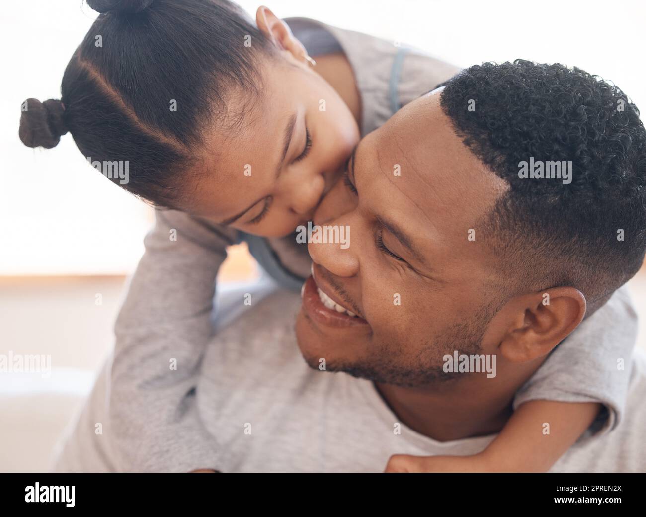 Primo piano adorabile bambina sorridendo e abbracciando il suo singolo padre dentro a casa. Carino gara mista bambino godendo del tempo libero del fine settimana con un singolo genitore Foto Stock