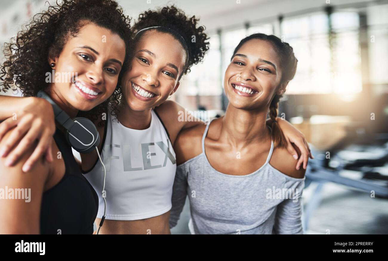 Tutti hanno bisogno di un amico solidale al loro fianco, un gruppo di giovani donne felici che si divertono insieme in palestra. Foto Stock