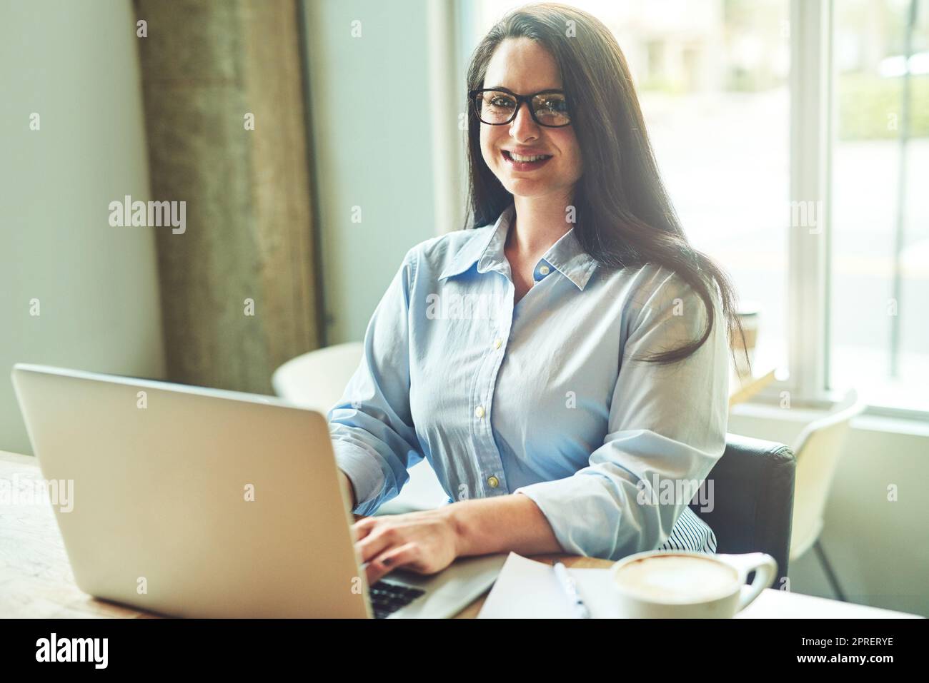 Il vantaggio più grande del freelancing che lavora quando e dove. Ritratto di una giovane donna che utilizza un computer portatile in un bar. Foto Stock