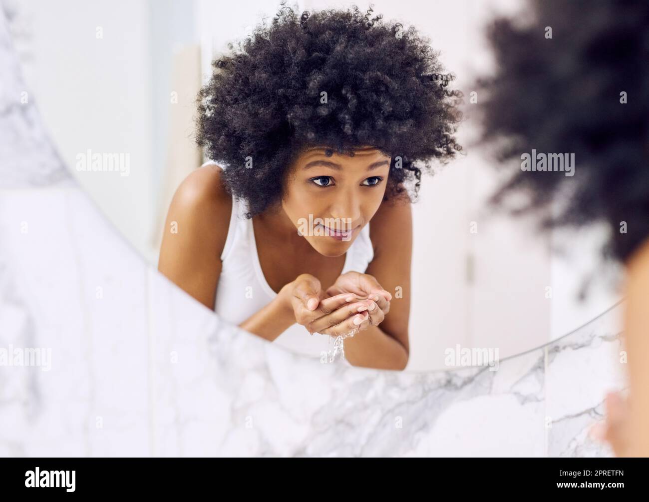 È il momento di iniziare il mio regime di bellezza. Una giovane donna attraente lavare il viso in bagno a casa. Foto Stock