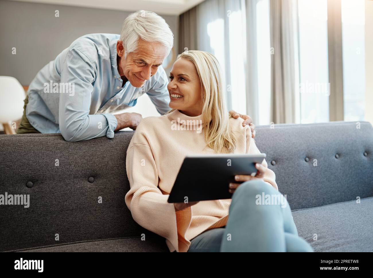 Ehi miele, dai un'occhiata a questo. Una coppia matura che usa un tablet digitale sul divano di casa. Foto Stock