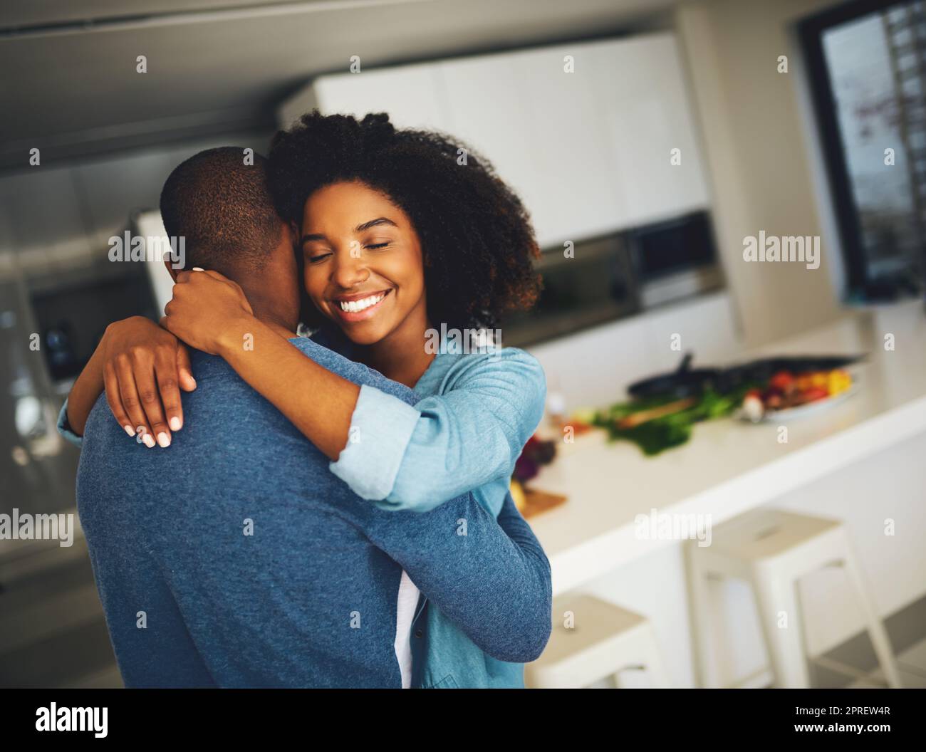 Voglio rimanere così per sempre. Una giovane coppia allegra che si tiene a vicenda e che condivide un tenero momento in cucina a casa durante il giorno. Foto Stock