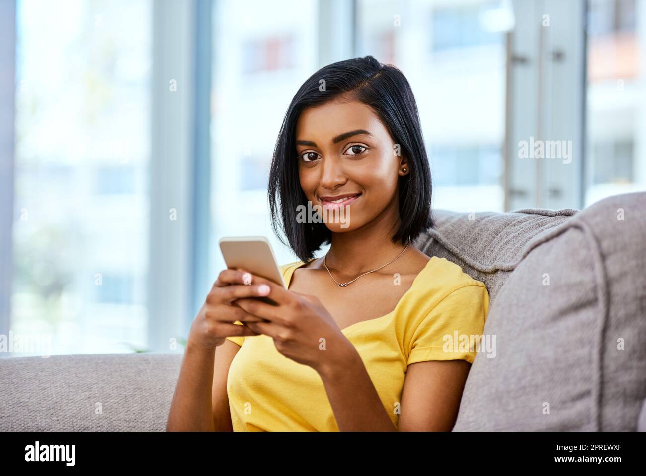 Accedere ai social media online con i social media. Una ragazza adolescente che usa un cellulare a casa. Foto Stock