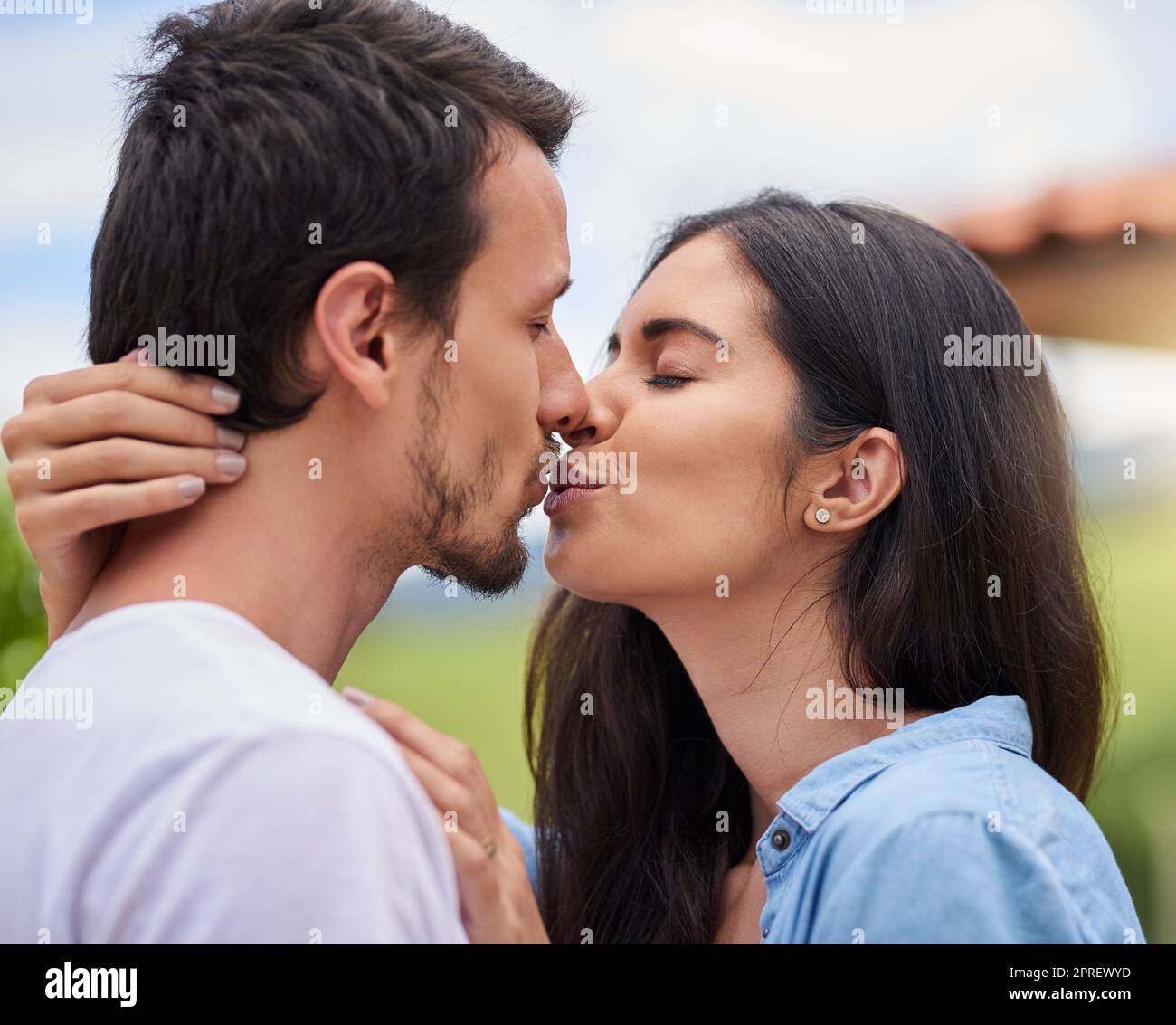 Baciami come mi manchi, una giovane coppia affettuosa che bacia mentre si è in piedi all'aperto. Foto Stock