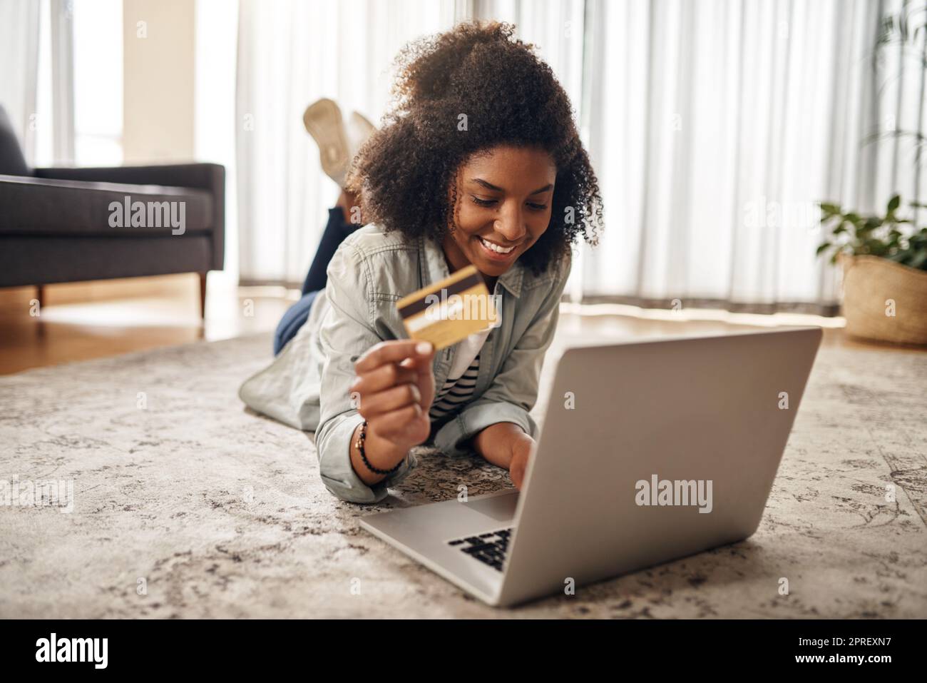 La spedizione è molto più veloce in questi giorni. Una giovane donna che tiene la sua carta di credito mentre usa il suo laptop. Foto Stock