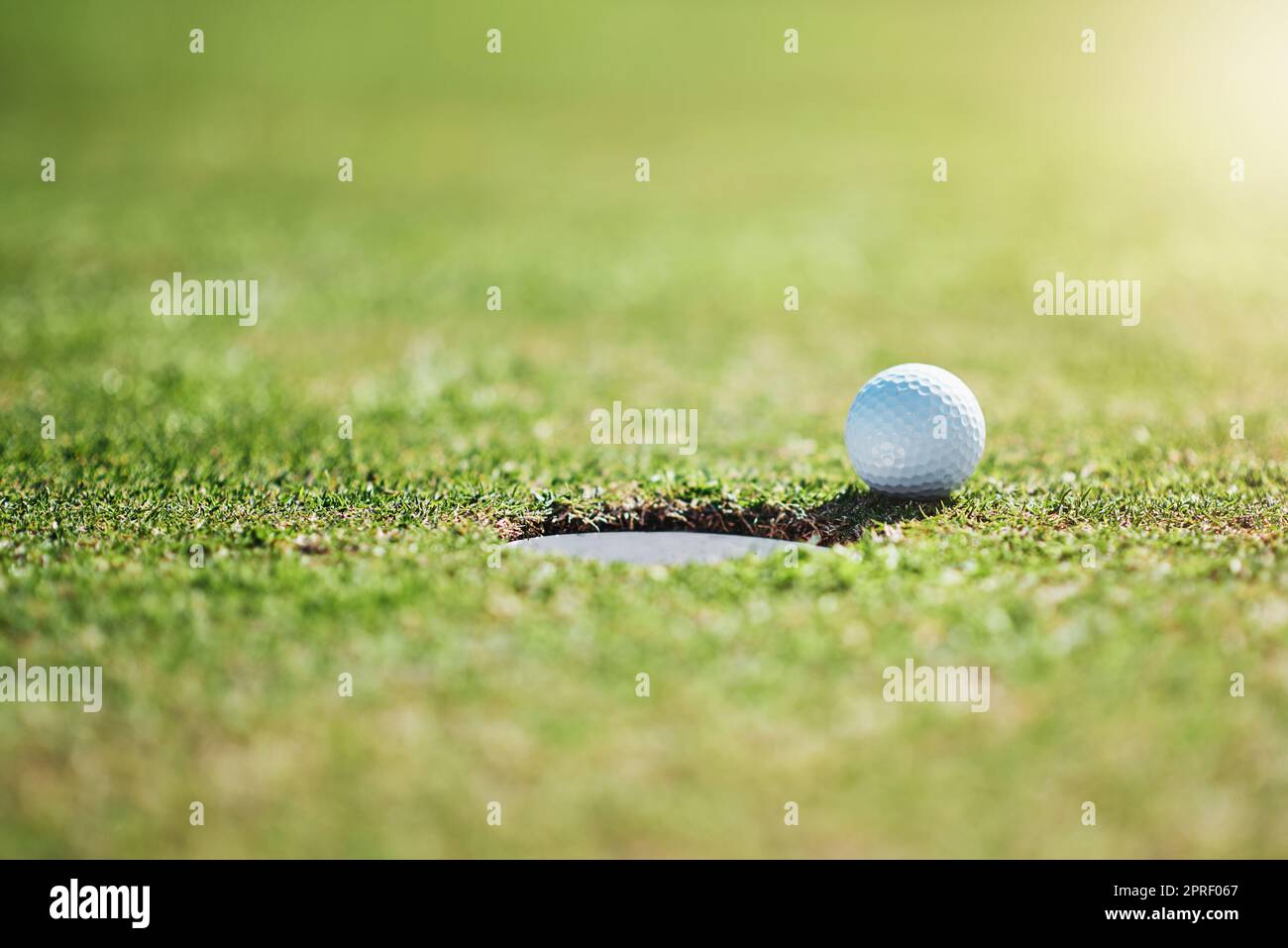 Così vicino ma nessun sigaro. Colpo di primo piano di una palla da golf sul bordo di una buca all'aperto su un campo da golf durante il giorno. Foto Stock