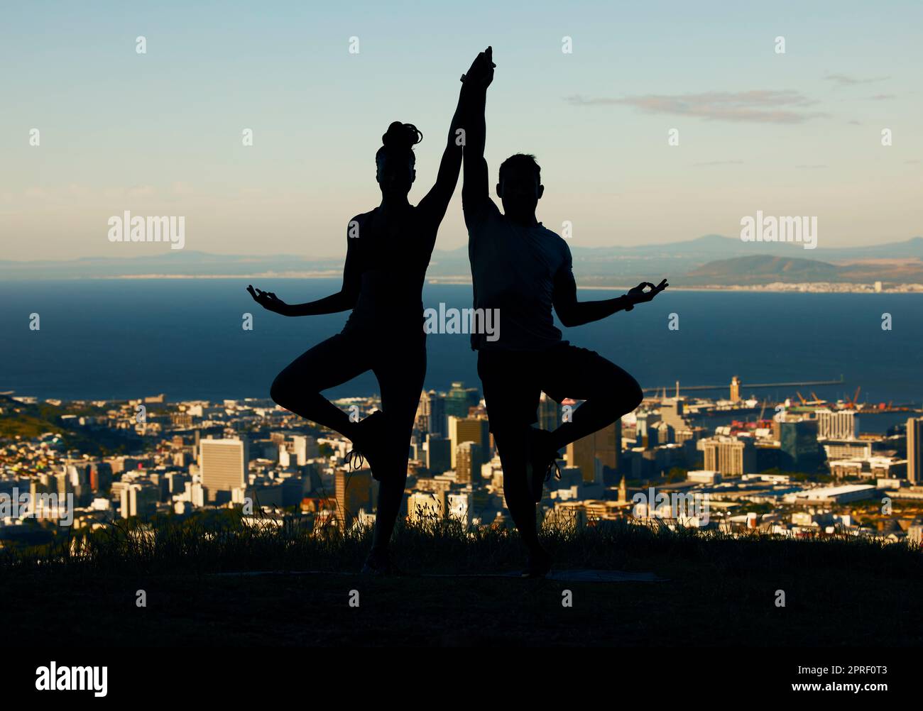 Coppia, silhouette e yoga in forma spirituale e benessere sullo sfondo di una città. Ombra scura della gente nell'equilibrio di esercitazione di meditazione insieme Foto Stock