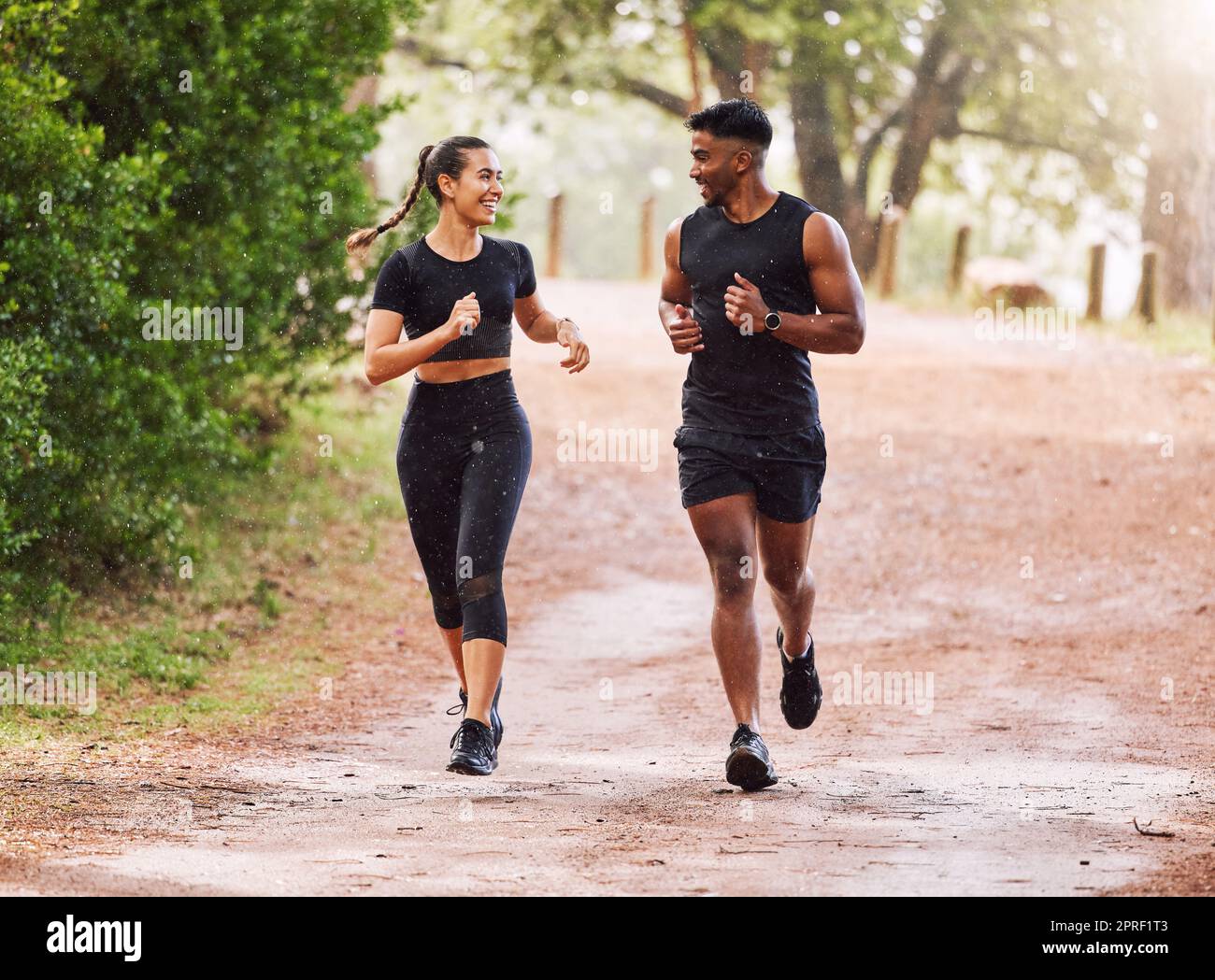 Fitness, esercizio fisico e coppia felice che corre o fa jogging su un sentiero nella foresta o su un parco all'aperto. Uomo e donna sportivi e sorridenti che mantengono attiva e in forma durante l'allenamento e l'allenamento Foto Stock