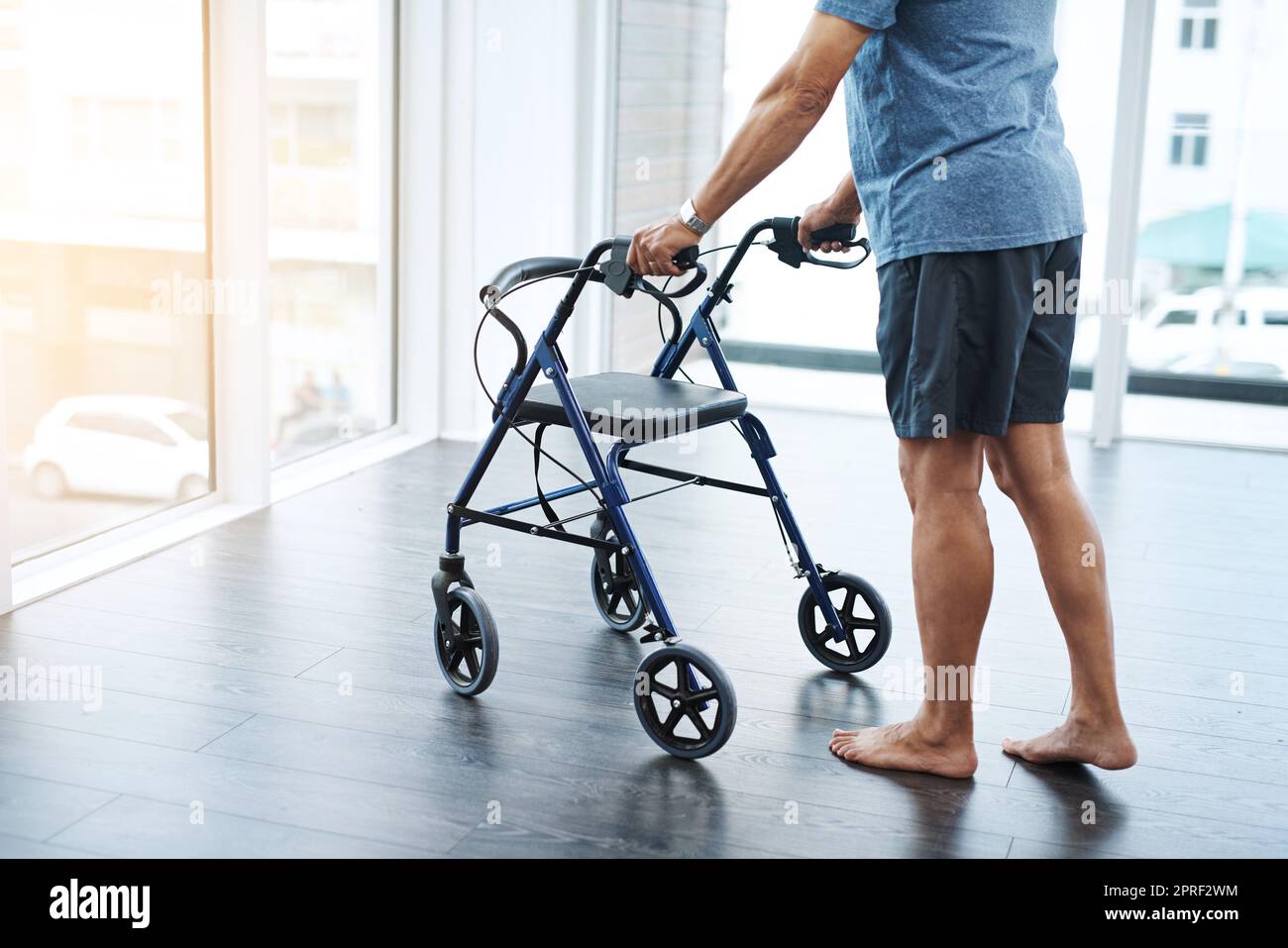 Basta fare qualche semplice passo. Un uomo maturo irriconoscibile che spinge un camminatore per aiutare a riabilitare il suo movimento in una clinica. Foto Stock